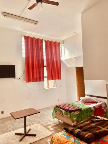 a room with two beds and a table and red curtains at Hotel Cetro in Belo Horizonte