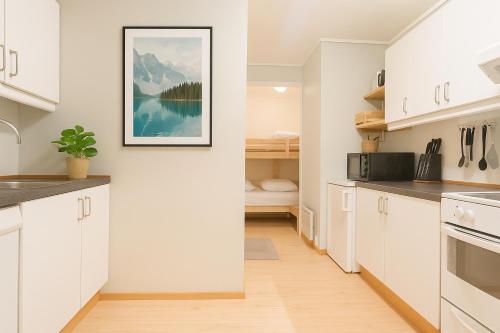 Una cocina con gabinetes blancos y un cuadro en la pared. en Delightful Bryggen Apartment - Norwegians Minimum Age 25, en Bergen