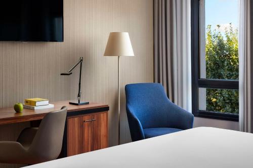 Habitación de hotel con cama, escritorio y silla azul en NH Ciudad de Cuenca, en Cuenca