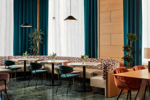 a restaurant with tables and chairs and blue curtains at NH Ciudad de Cuenca in Cuenca