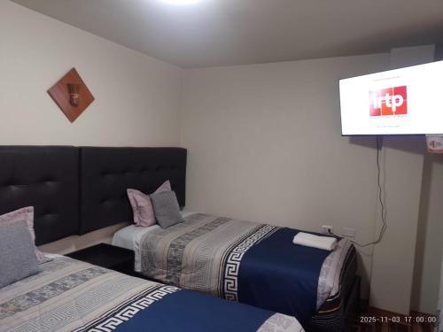 a room with two beds and a flat screen tv at San Antonio hotel in Puno