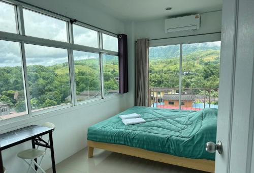 a bedroom with a bed and a large window at อิงเขาค้อ in Campson