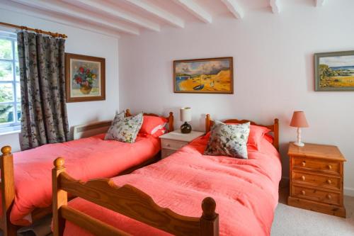 two beds in a bedroom with red sheets at St Michaels in Porthleven