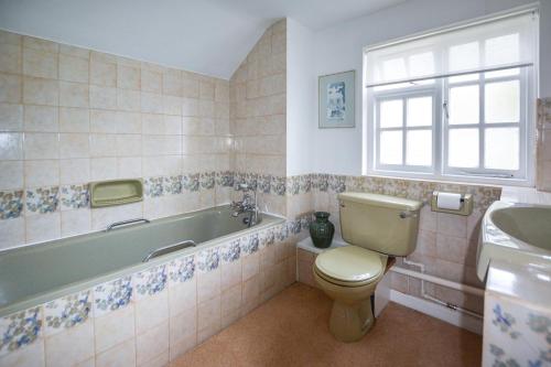 a bathroom with a toilet and a tub and a sink at St Michaels in Porthleven