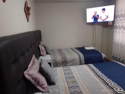 a bedroom with two beds and a flat screen tv at San Antonio hotel in Puno