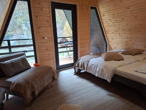 two beds in a room with windows and a chair at Escape Remeti - Aframe by the River in Remeţi
