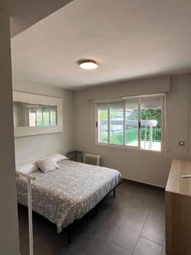 a bedroom with a bed and two windows at APARTAMENTOS URDAIBAI 4 in Busturia
