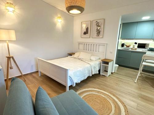 Un dormitorio con una cama y un sofá y una cocina. en Refúgio junto à falésia, en Olhos de Água