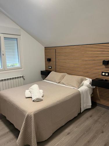 a bedroom with a large bed with a wooden headboard at Pensión Ferreiriño in Quiroga