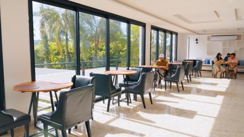 une chambre avec des tables, des chaises et de grandes fenêtres dans l'établissement Villa Santorini Boutique & Hotel, à Pirenópolis