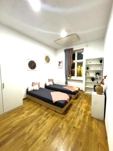 een slaapkamer met twee bedden en een houten vloer bij Pokoje przy Rynku IV in Katowice