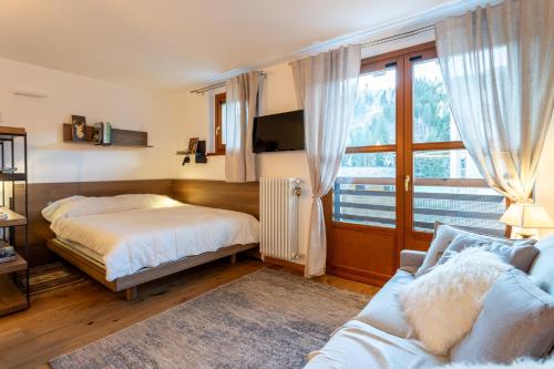 a bedroom with a bed and a couch and a window at Monolocale in centro a Madesimo in Madesimo