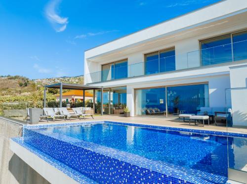 a villa with a swimming pool and a house at Lê Maison Deluxe Madeira - Where Peace is breathed and Luxury is felt! in Ribeira Brava