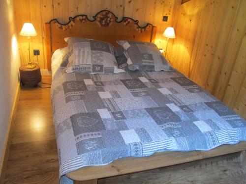 a bed with a blue and white quilt in a room at Appartement Du Dou Des Ponts in Pralognan-la-Vanoise