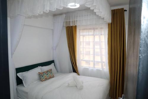 a bedroom with a white bed and a window at Makasembo Cozy Serenity in Kisumu