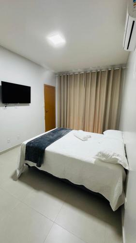 a bedroom with a large bed and a flat screen tv at Casa 3 suítes Salinas in Salinópolis