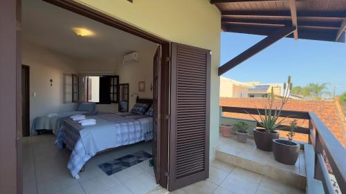 a bedroom with a bed on a balcony at Aconchego e diversão em Peruíbe sobrado com estrutura completa para sua família ar condicionado, churrasqueira ,academia, cervejeira, piscina in Peruíbe