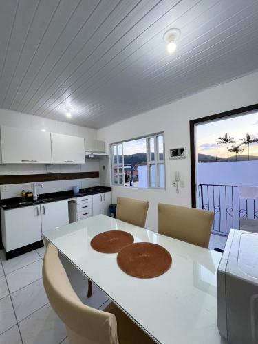 a kitchen with a table and chairs and a kitchen with a view at Apartamento Orquídea in Porto Belo
