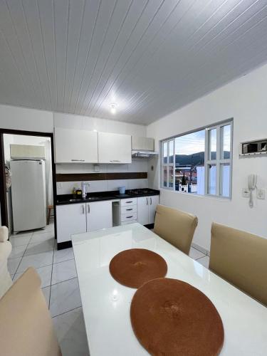 a kitchen with a table and chairs and a kitchen with white cabinets at Apartamento Orquídea in Porto Belo