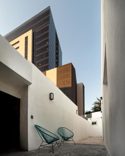 two green chairs sitting on the side of a building at Adhoc Barrio Antiguo in Monterrey