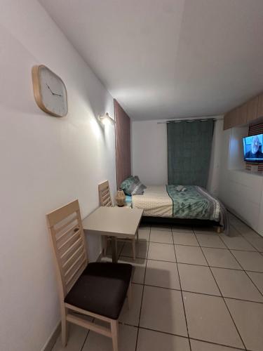 a bedroom with a bed and a table and a clock at Le Clos d'AIX studio 211 in Aix-en-Provence