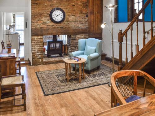 ein Wohnzimmer mit einem Stuhl und einem Tisch und einer Uhr in der Unterkunft The Old Sweet Shop in Kings Lynn