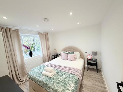 ein Schlafzimmer mit einem Bett mit rosa Kissen und einem Fenster in der Unterkunft Bright Modern Apartment in Northfield