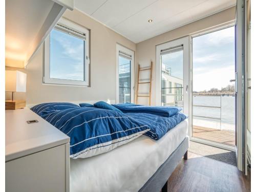 a bedroom with a bed and a desk and windows at Bright Base with Coastal Access in Ribnitz-Damgarten