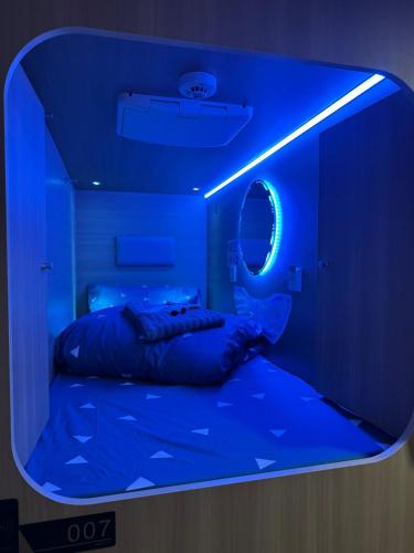 een bed in een kamer met een blauw licht bij The GreenHouse Capsules in Londen