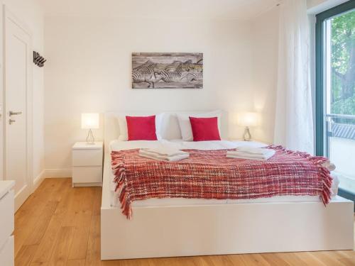 a white bedroom with a large bed with red pillows at Freya - with breathtaking sea views in Sassnitz