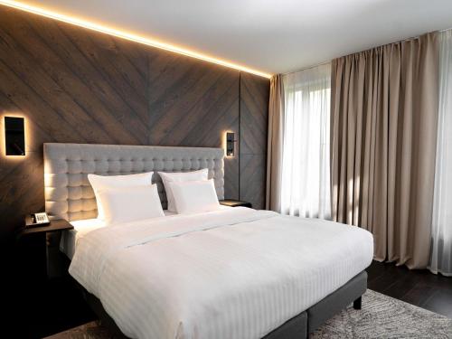 1 dormitorio con 1 cama blanca grande y pared de madera en Pullman Riga Old Town - Renovated 2025, en Riga