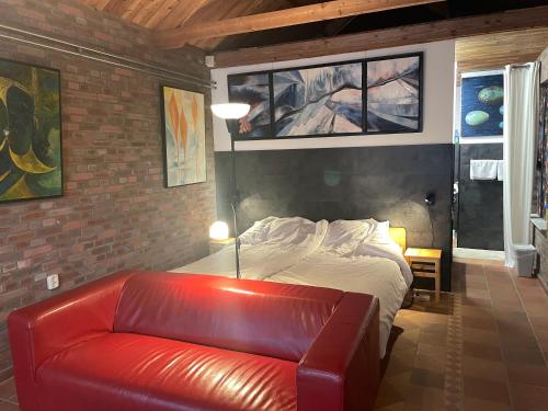 a bedroom with a bed and a red leather couch at 't ouw ateljeeke in Budel
