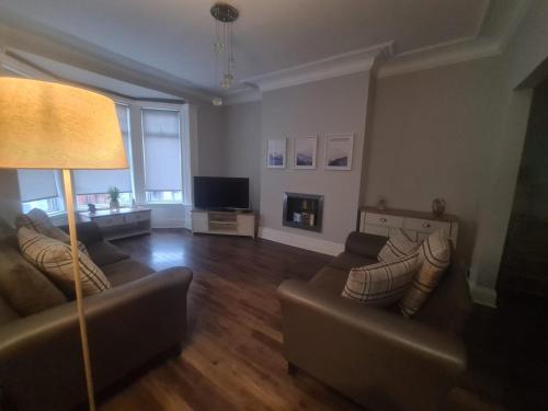 een woonkamer met 2 banken en een televisie bij Coastal town properties in Jarrow