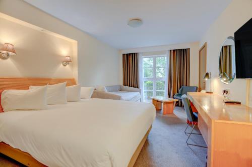 een hotelkamer met een groot bed en een bureau bij Sunday London Staines-upon-Thames Heathrow T5 in Staines