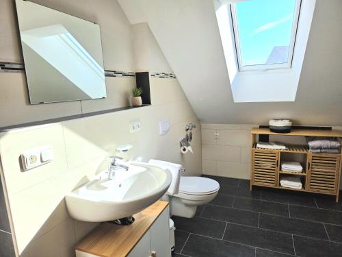 a bathroom with a sink and a toilet with a skylight at Rost Apartments - Staffelsee 