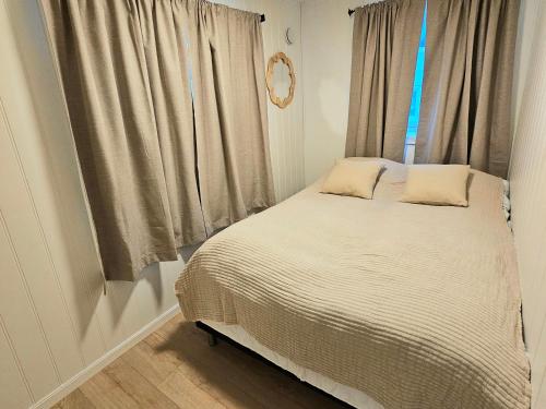 a bed with two pillows in front of a window at Fin 3-roms leilighet i Harstad sentrum in Harstad