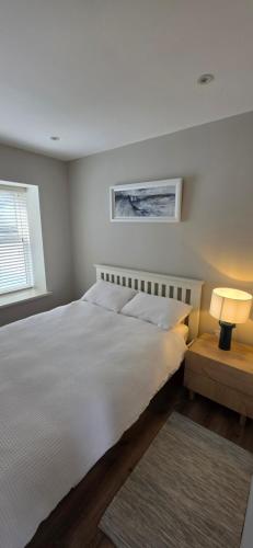 a bedroom with a large white bed and a window at Turtle Cove in Portrush