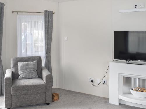 Una sala de estar con una silla y un televisor. en Sunnyside Lodge, en Sandown