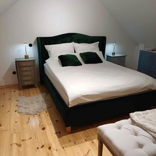 a bedroom with a large bed with two green pillows at Siedlisko 3 Stodoły Bałtów - SPA w naturze in Bałtów