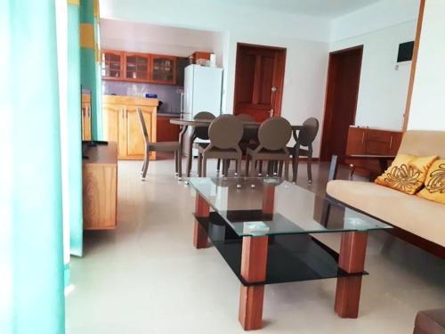 a living room with a glass table and chairs at Beachfront apartment-perfect sea escape! in Flic-en-Flac