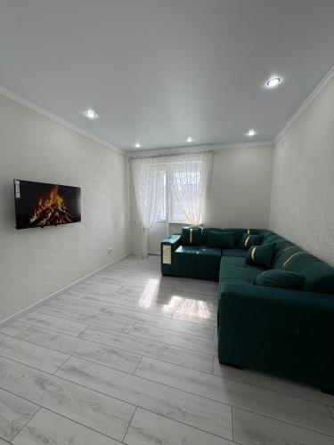 a living room with a green couch and a fireplace at ЖК Арман кала 1- комнатная квартира in Zhezdi
