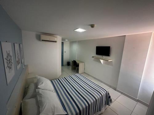 ein Schlafzimmer mit einem Bett und einem Fernseher an der Wand in der Unterkunft Aracaju Corais Hotel in Aracaju