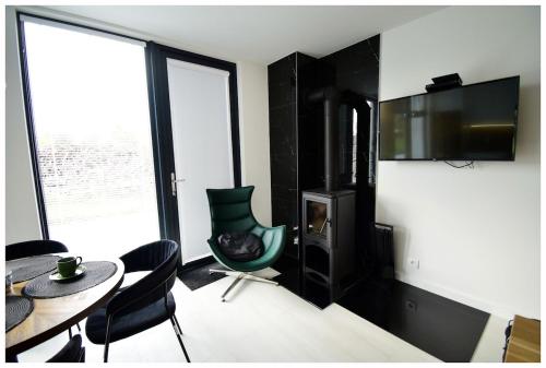 a living room with a table and chairs and a television at Biała chatka w Krzaczastym Zakątku 