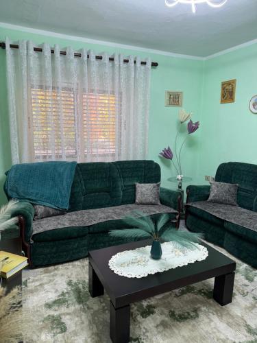 a living room with a green couch and a table at Sweet Escape in Shkodër
