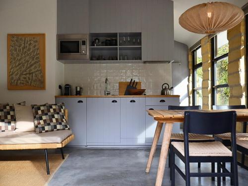 a kitchen with white cabinets and a table and chairs at Vakantiehuisjes Theodorus en Josephine - Landgoed Heerdeberg- Maastricht in Cadier en Keer