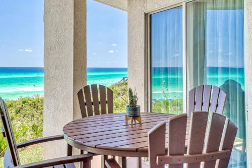 a wooden table and chairs on a balcony with the ocean at HP 15W Salt and Light by 30A Escapes in Rosemary Beach