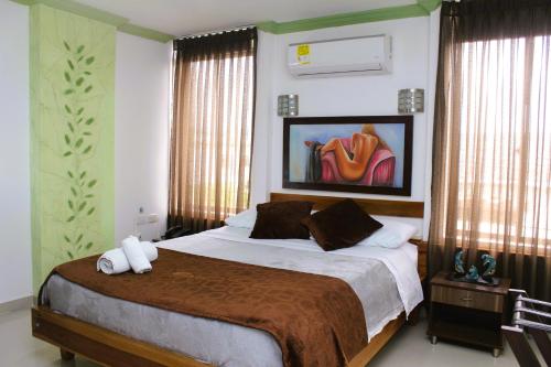 a bedroom with a large bed and a painting on the wall at HOTEL NOGAL PLAZA in La Virginia