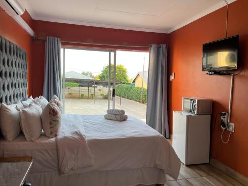 een slaapkamer met een bed en een groot raam bij 7th Dimension Guesthouse in Zeerust