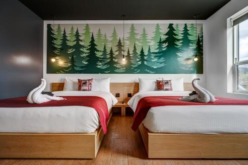 Dos camas en una habitación con un cuadro de árboles. en Raven Inn Whitehorse, en Whitehorse