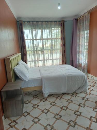 a bedroom with a bed and a large window at Kio Farm Retreat in Kiserian